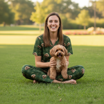 Woman sitting on grass holding a small dog, both wearing green outfits with animal patterns.