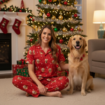Woman in red pajamas with a dog in front of a Christmas tree and fireplace.